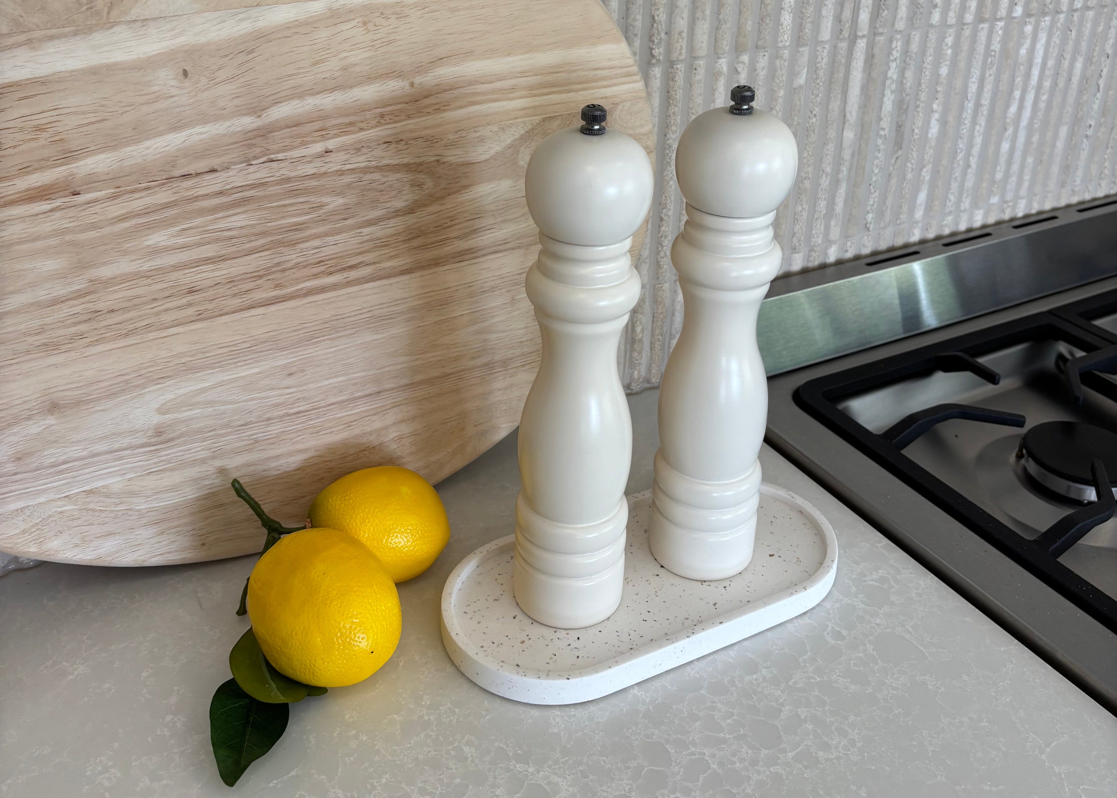 Seashell specked tray on kitchen bench, salt and pepper grinders and lemons